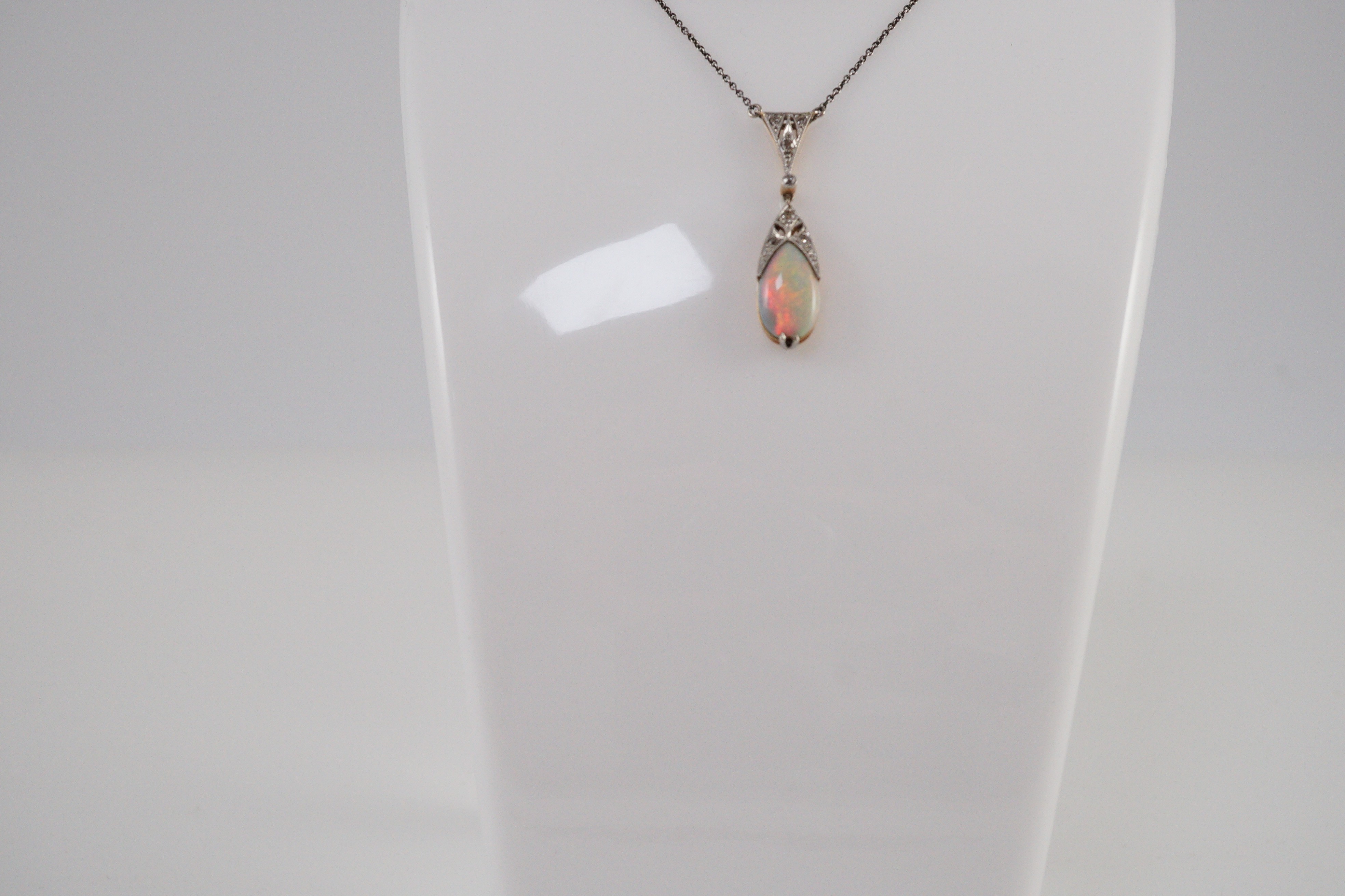 A 1920's gold and platinum, white opal and millegrain set diamond cluster pear shaped drop pendant necklace